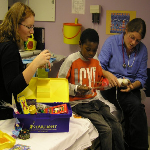 A young child looking through the distraction box whilst a medic is treating their arm.